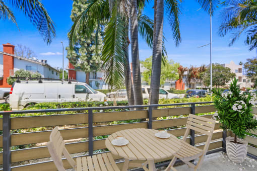 a patio with a table and chairs and palm trees