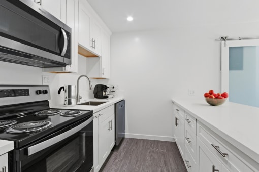 a kitchen with white cabinets and black appliances and a sink