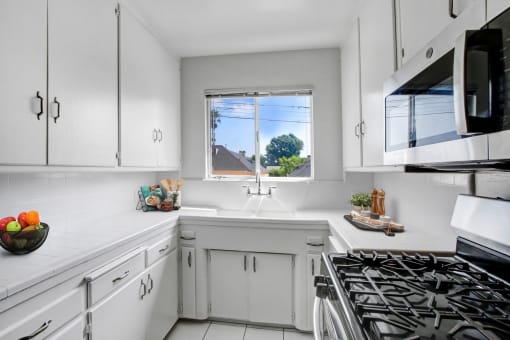 a kitchen with white cabinets and a window