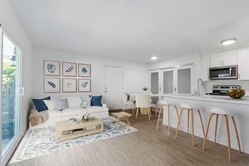 a living room with a couch and a kitchen with a breakfast bar and a window
