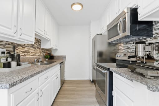 a kitchen with white cabinets and granite counter tops and stainless steel appliances