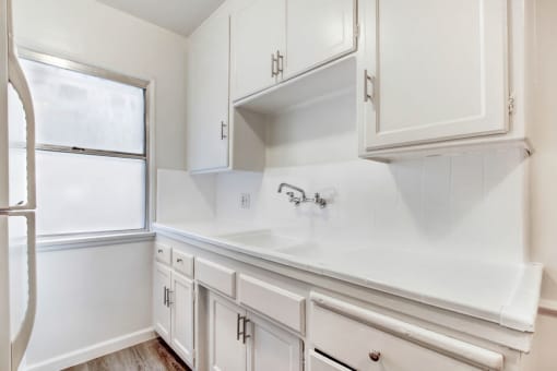 a kitchen with white cabinets and a window