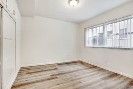 a bedroom with hardwood floors and a large window