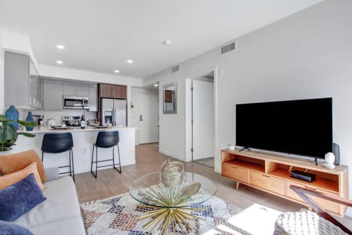 a living room with a tv and a kitchen in the background