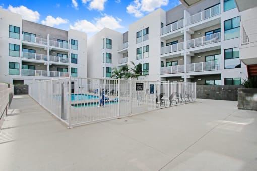 an apartment building with a fence and a pool in front of it