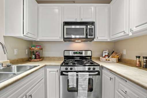 A kitchen with white cabinets and a black microwave above the stove.