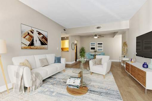A living room with a white couch, a coffee table, and a painting on the wall.