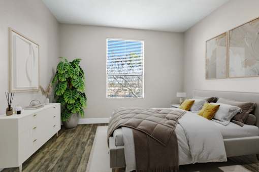 A bedroom with a bed, a dresser, and a potted plant.