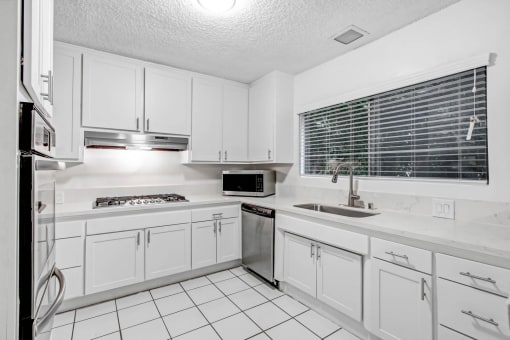 a white kitchen with white cabinets and a sink