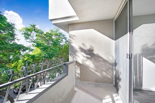 a balcony with a door and a view of a tree