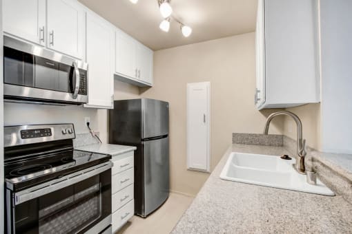 a kitchen with white cabinets and black appliances and a sink