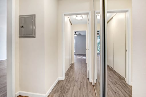 a renovated living room with a mirror and a hallway to a bathroom