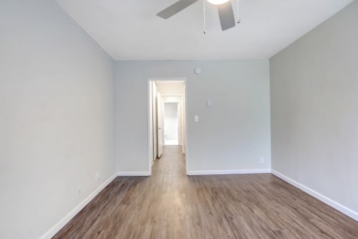 an empty living room with wood floors and a ceiling fan