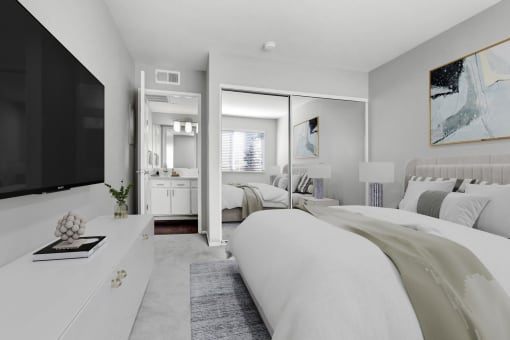 a white bedroom with a large bed and a tv