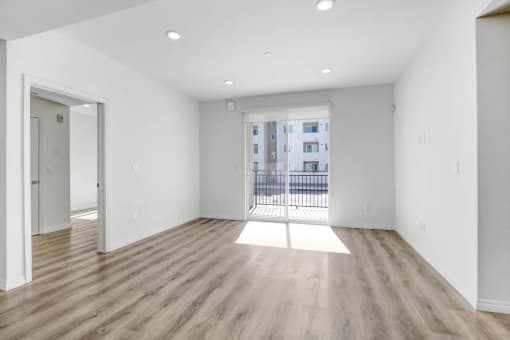an empty living room with wood floors and a balcony