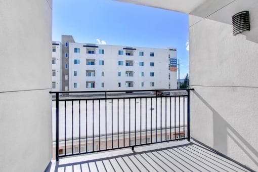 a balcony with a black railing and a white building in the background