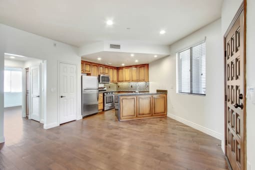 an empty kitchen with wooden cabinets and a stainless steel refrigerator
