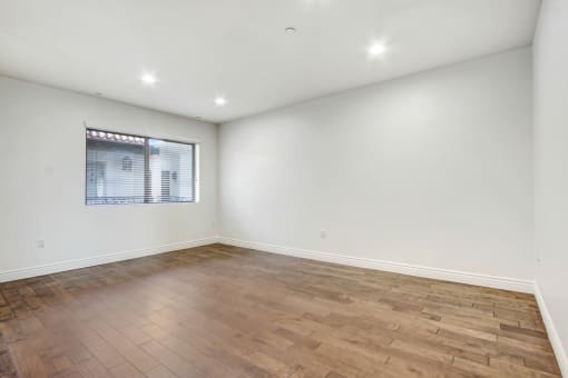 an empty living room with wood flooring and a window