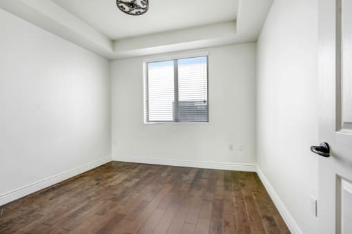 an empty living room with wood floors and a window