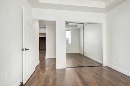 an empty living room with a mirrored closet door