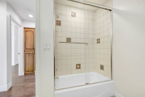 a white tiled bathroom with a tub and a shower