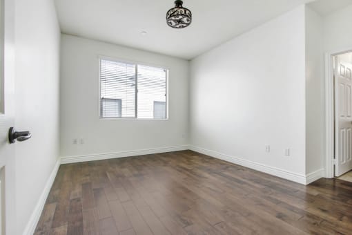 an empty living room with white walls and a window