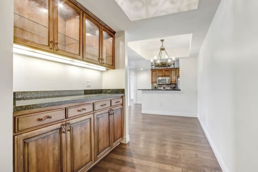 a kitchen with wooden cabinets and a hallway to a living room