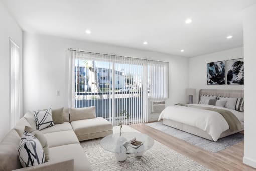 a white bedroom with a bed and a couch and a table