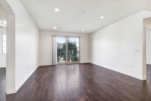 an empty living room with white walls and a sliding glass door