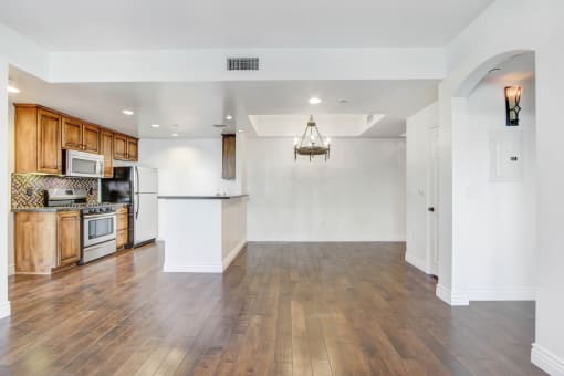the living room and kitchen of a new home with wood floors and white walls
