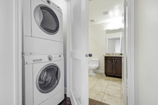 a white washer and dryer in a bathroom with a toilet and a sink