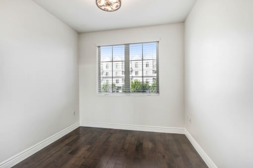 an empty living room with a window and hardwood floors