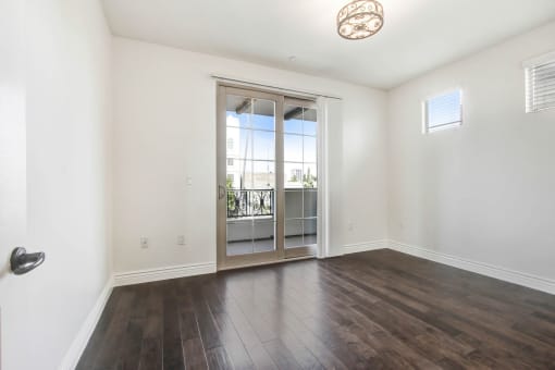an empty living room with a sliding glass door to a balcony