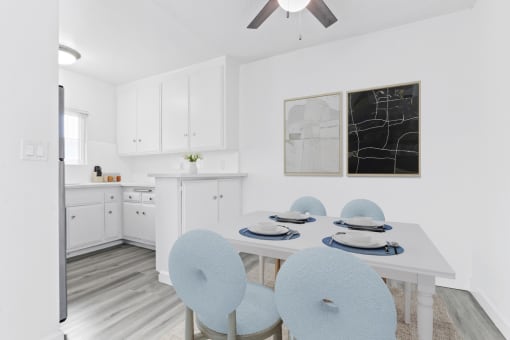 a white kitchen with a white table and blue chairs