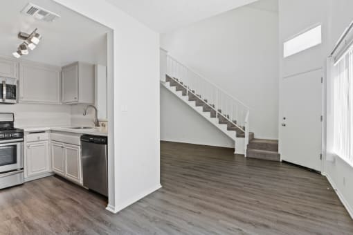 an empty kitchen and living room with white walls and wood flooring