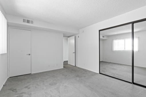 an empty living room with a large mirror and white walls