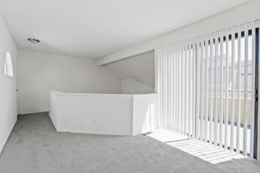 an empty living room with white blinds and a window