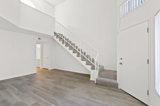 a white room with a staircase and a door to a hallway and a white door