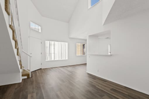 the living room and entryway of a house with white walls and wood floors