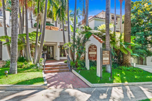 a house with palm trees and a sign in front of it