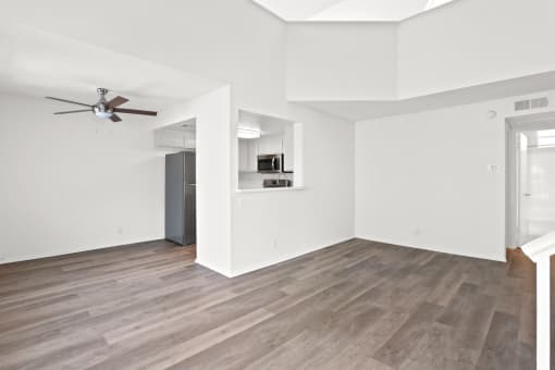 an empty living room with white walls and a ceiling fan