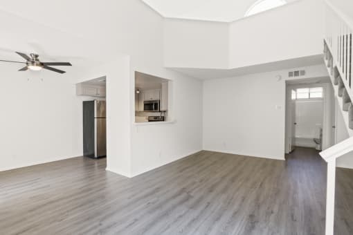 an empty living room with white walls and a ceiling fan