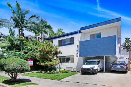 a white building with a blue roof and palm trees in front of it