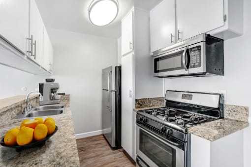 a kitchen with stainless steel appliances and a counter top with oranges
