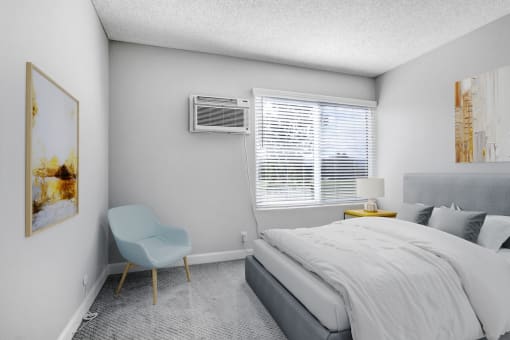 a bedroom with a bed and a chair and a window