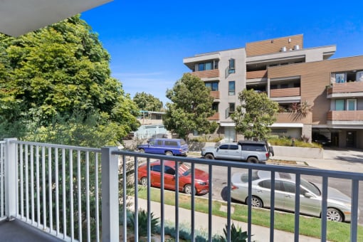 the view from the balcony of an apartment building with cars parked on the street