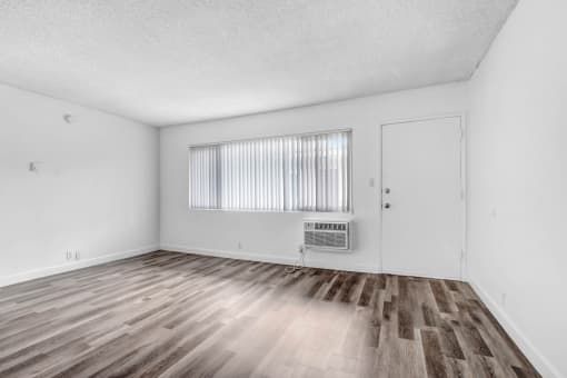the living room of an apartment with wood flooring and a window