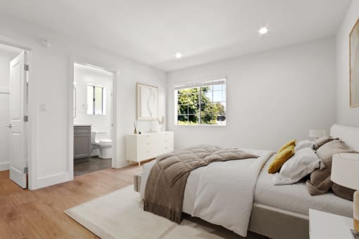 a white bedroom with a bed and a bathroom