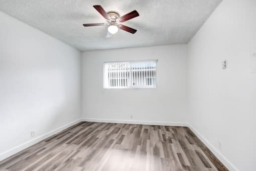 an empty living room with a ceiling fan and a window