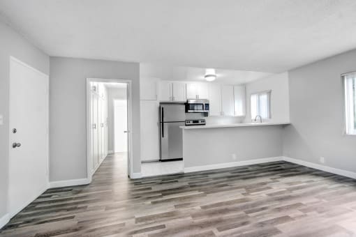 the living room and kitchen of an apartment with a hard wood floor